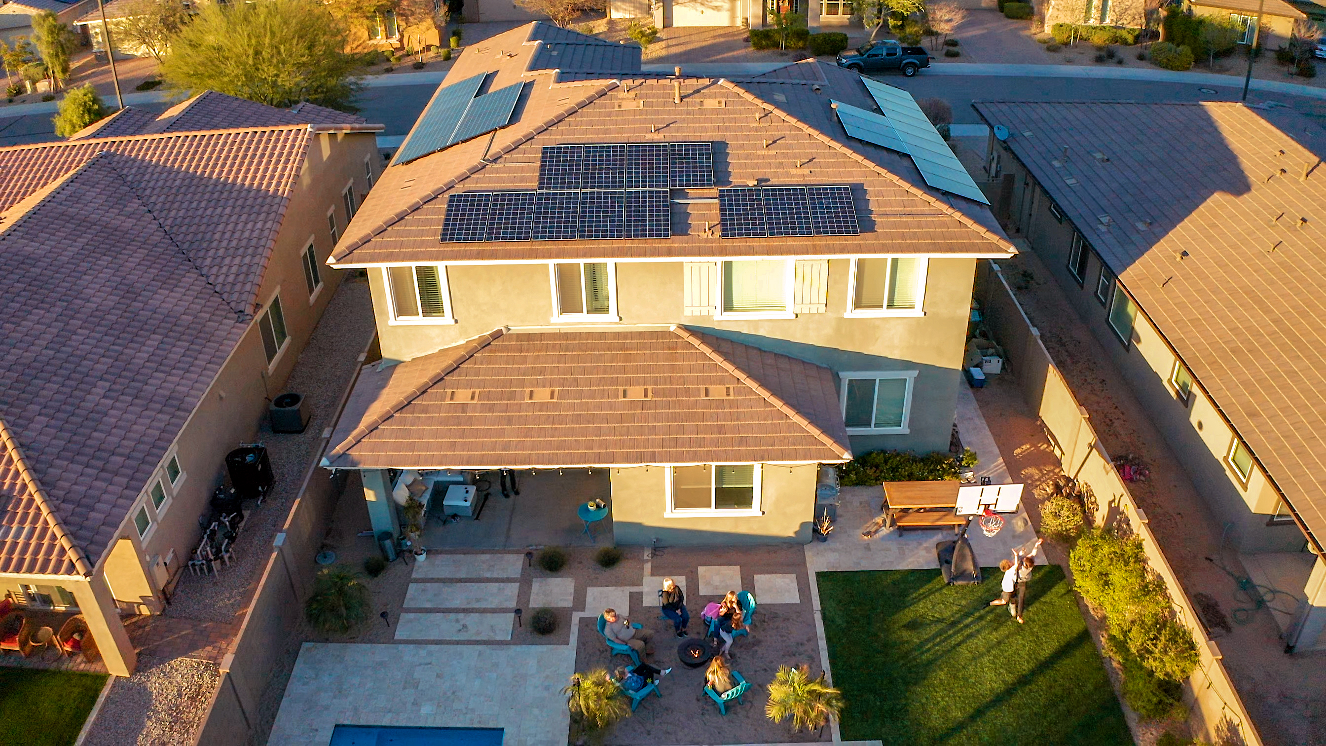 back yard of two story house at sunset with solar panels and solar battery